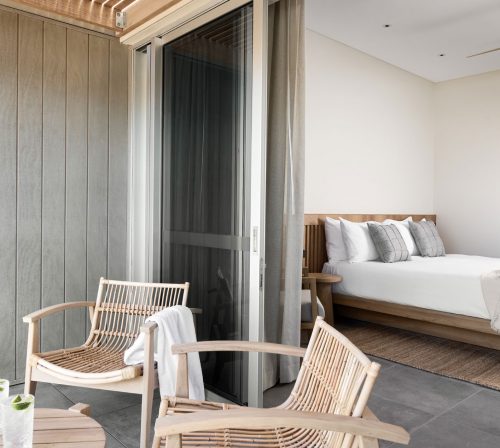 The private terrace in one of the Poolside rooms features outdoor chairs and a small table