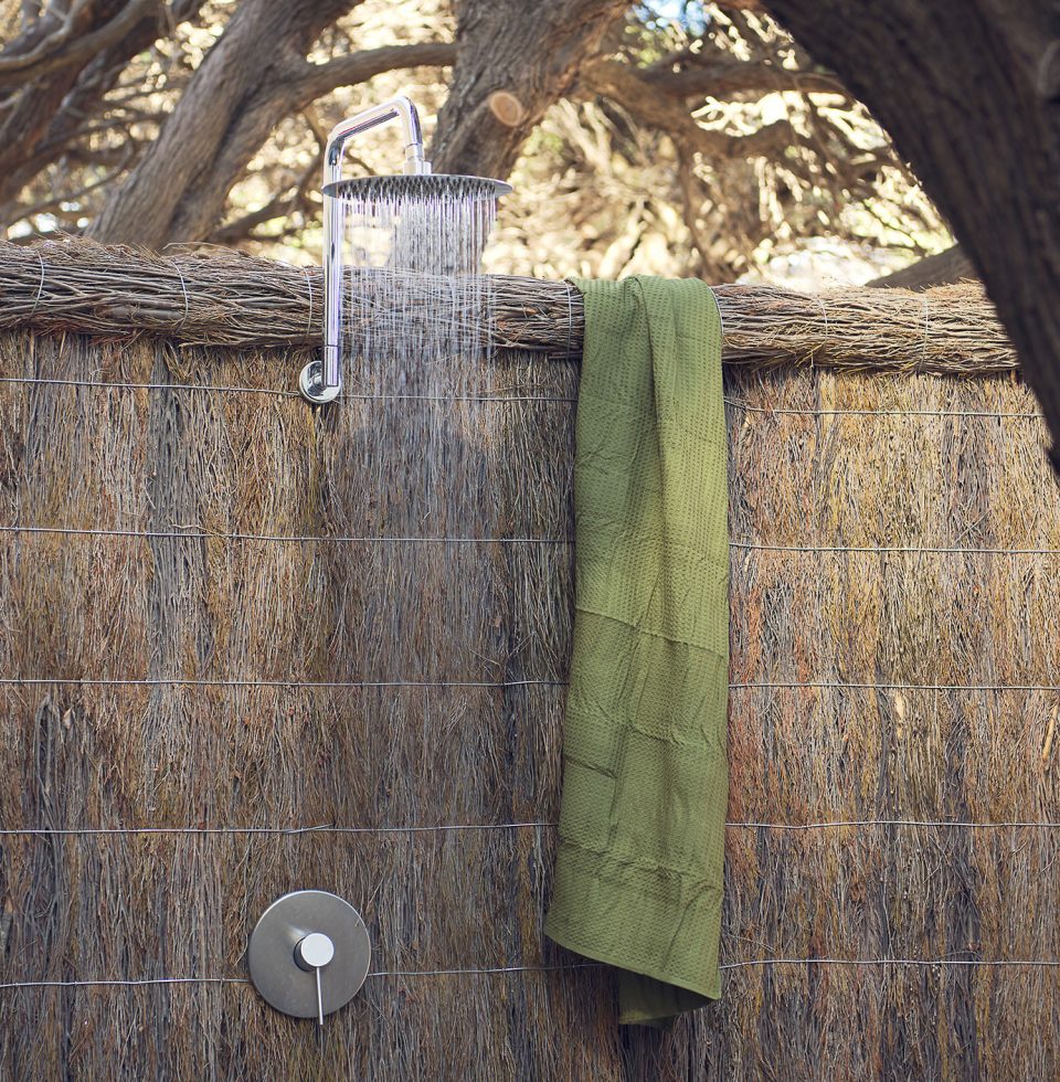 An outdor rain shower, hanging from a thatched wall