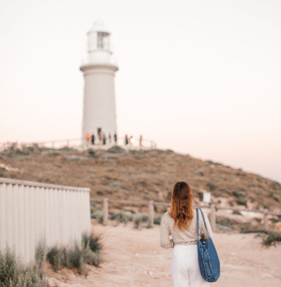 A tourist walks towards a lighthouse on Rottnest Island