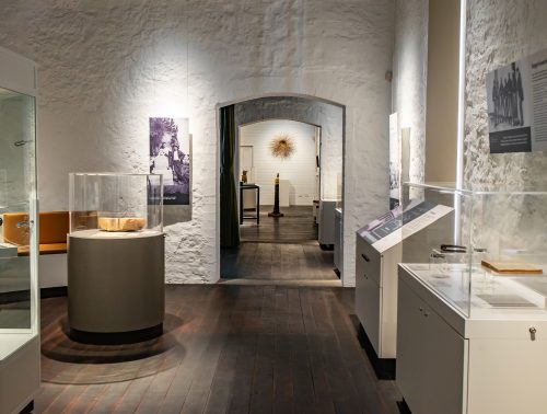 The interior of Wadjemup Museum shows historical photographs and artefacts in glass display cabinets