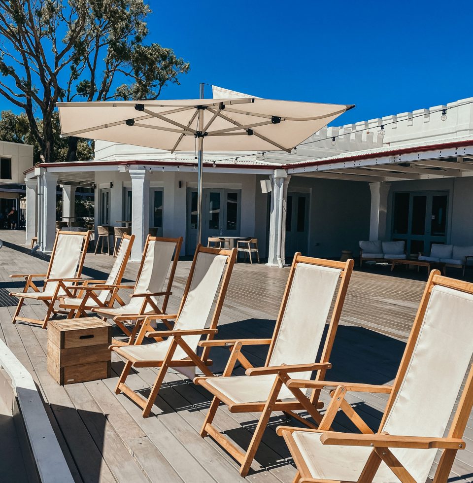 A row of deck chairs are arranged around an outdoor umbrella on the Seadeck at Samphire Rottnest