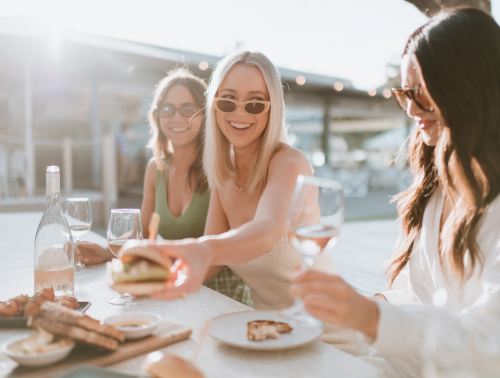 Three hotel guests share food and drinks at the Samphire Rottnest hotel restaurant