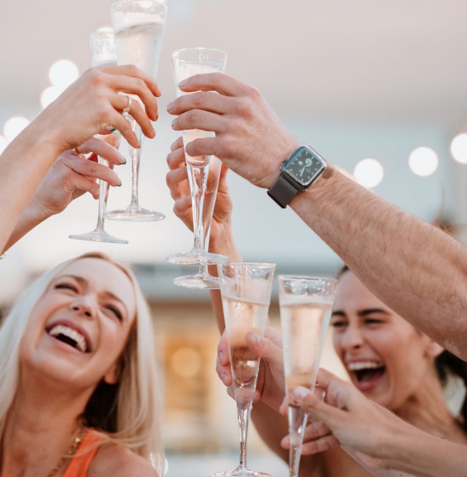 Hotel guests clink glasses of champagne together while smiling and laughing