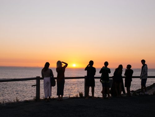 A group of tourists taking photos of a beautiful sunset on Rottnest Island