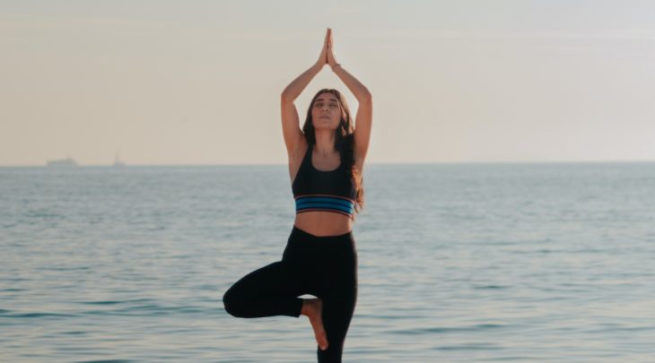 A woman practicing yoga on the beach