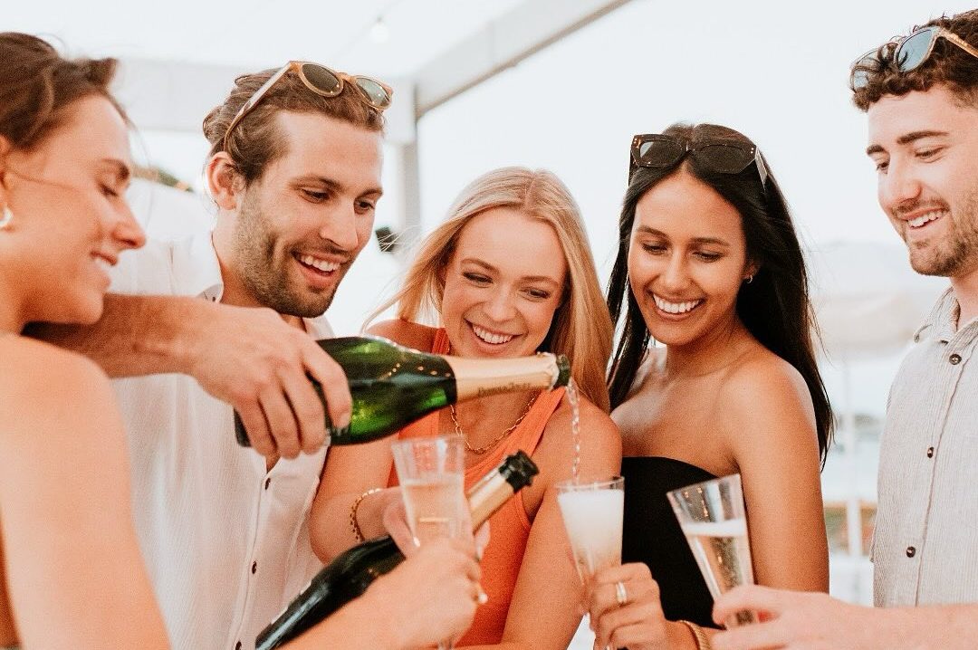Friends gathered around each other smiling and pouring a glass of champagne