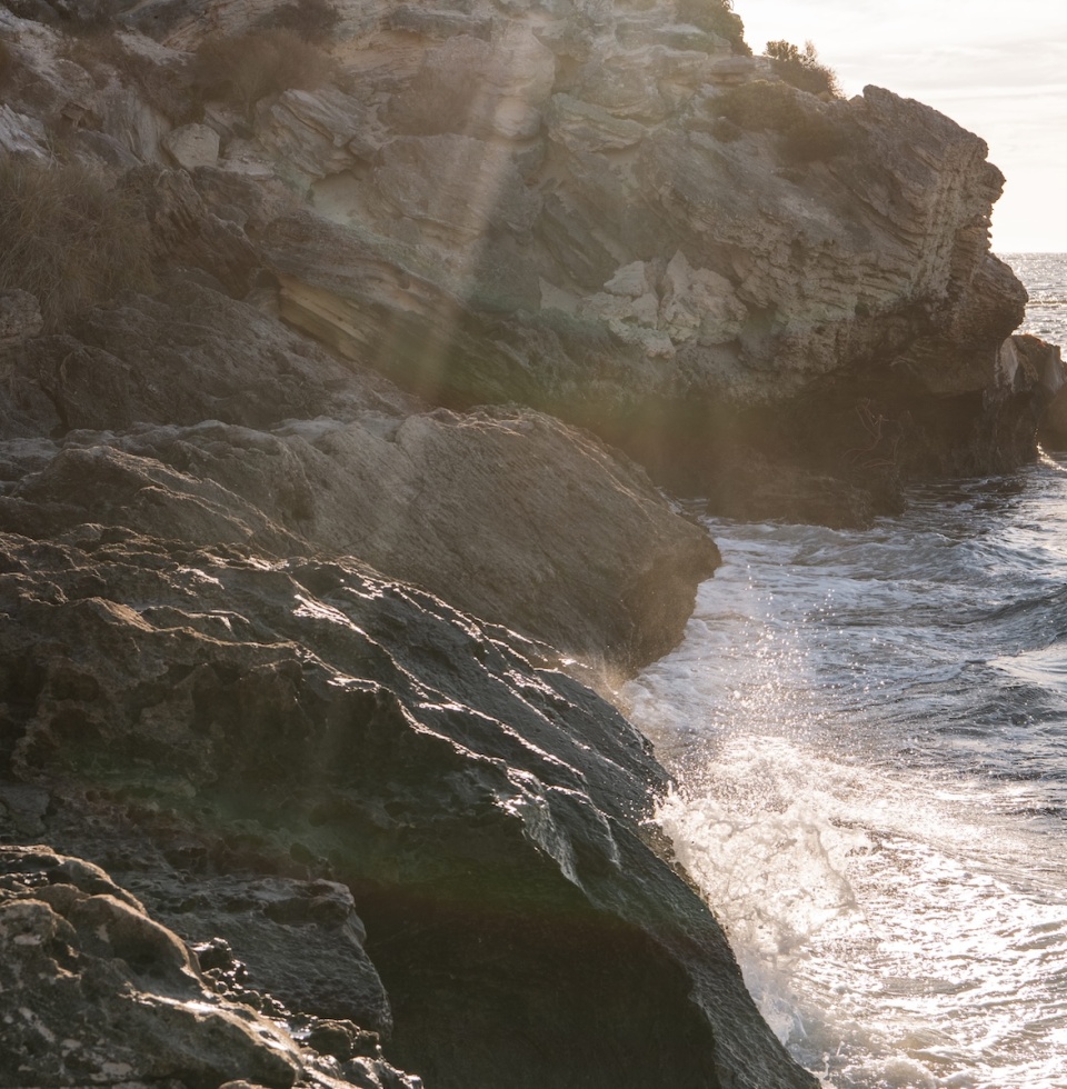 Waves crash against the rocks at Henrietta Rocks beach, at sunset