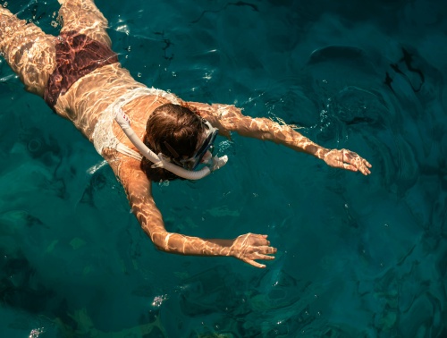close up birds eye view of a woman snorkelling in deep turquoise water