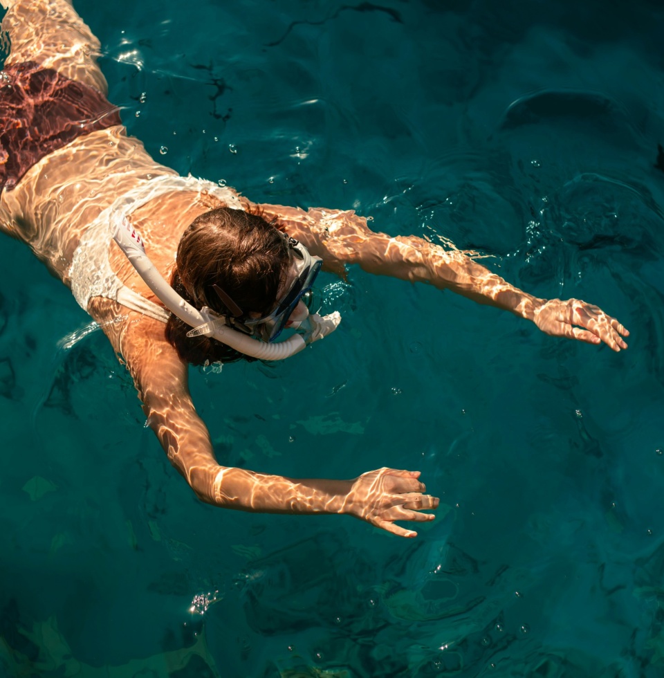close up birds eye view of a woman snorkelling in deep turquoise water
