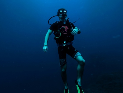 A scuba diver ascending from the vast deep blue