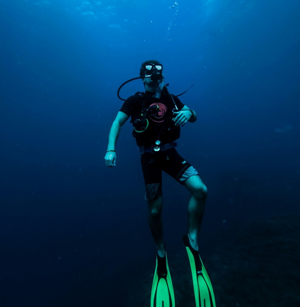 A scuba diver ascending from the vast deep blue